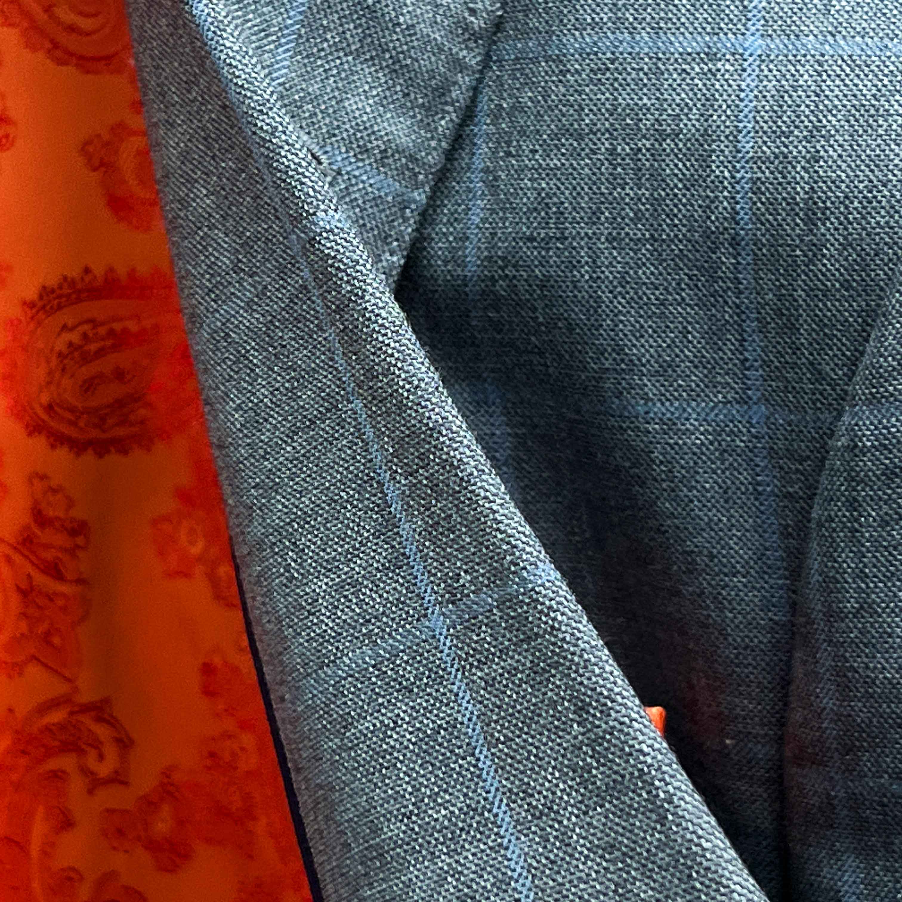 Detailed fabric texture view of Super 130's merino wool showing light gray base with light blue windowpane pattern