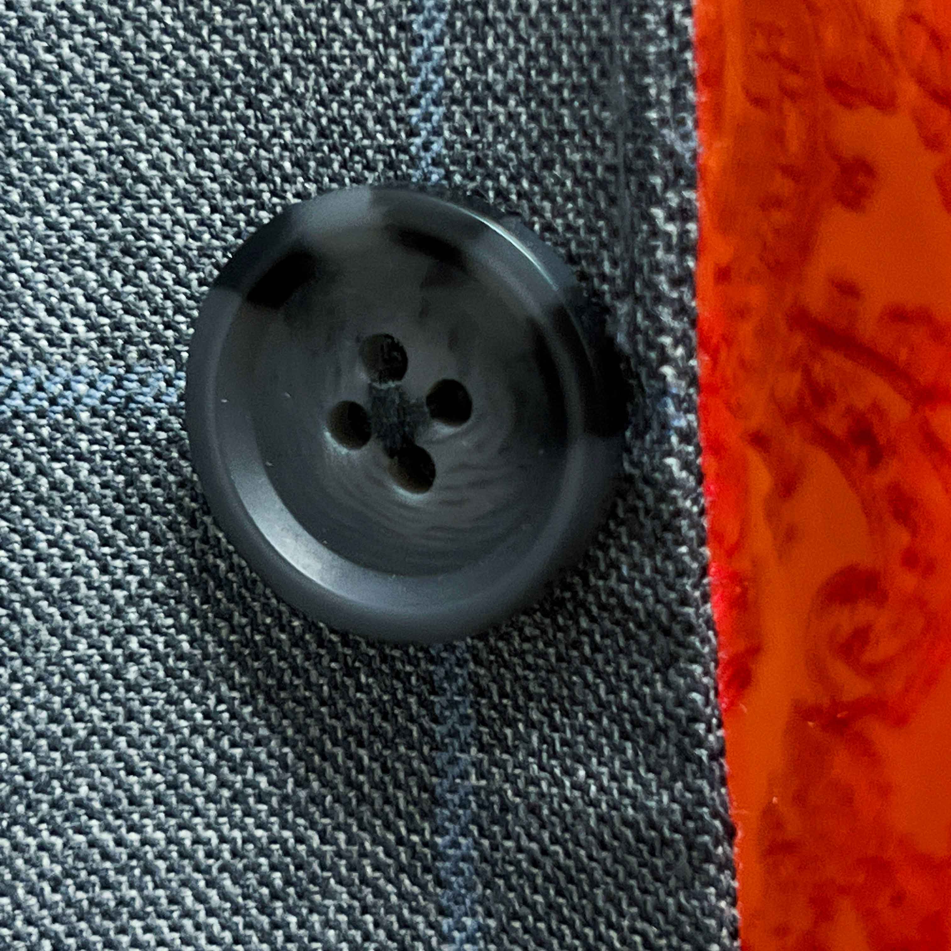 Close-up of dark gray horn buttons on light gray with light blue windowpane sport coat showing natural marble-like patterns