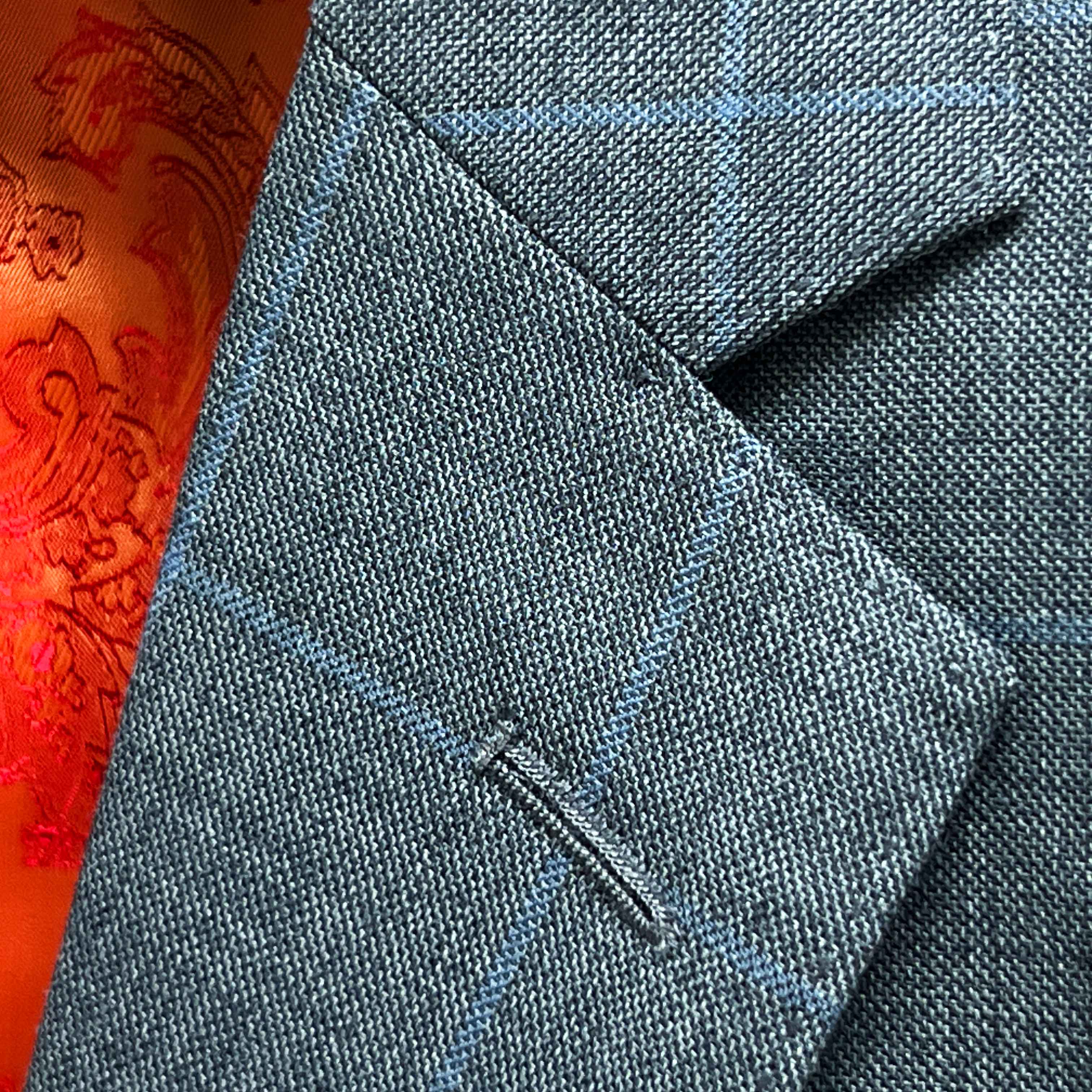 Classic notch lapel detail on light gray with light blue windowpane sport coat showing hand pick stitching and windowpane pattern