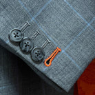Contrast bright orange accent buttonholes on light gray with light blue windowpane sport coat sleeve showing precise hand-finished stitching