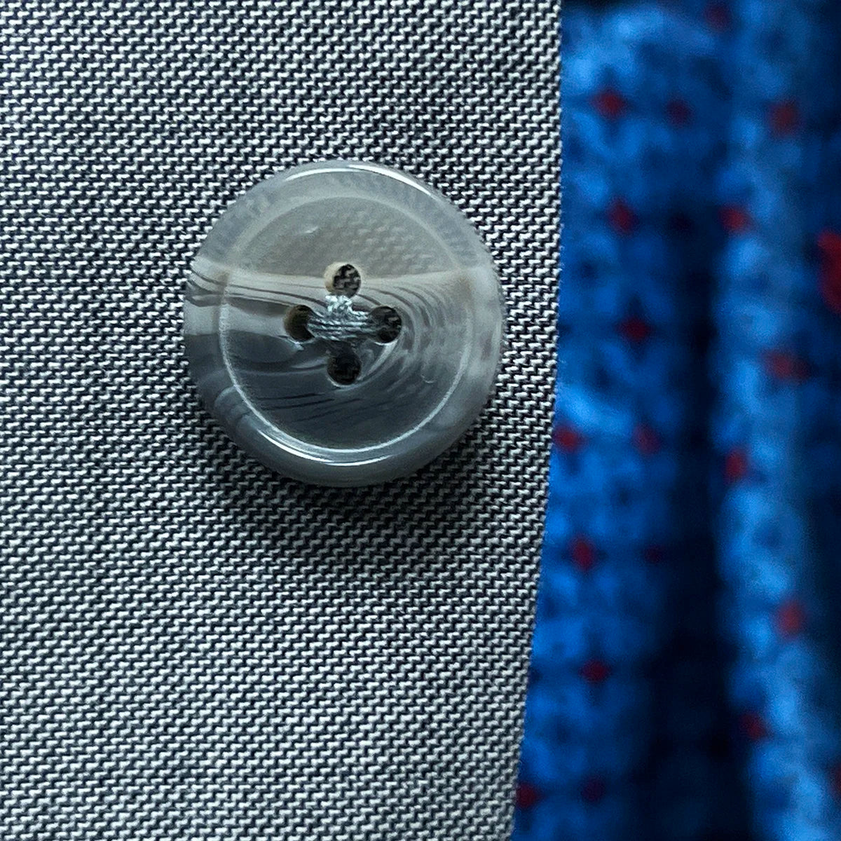 Detail of light grey horn buttons on suit jacket, showing natural marbling