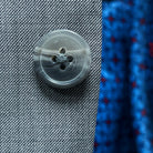 Detail of light grey horn buttons on suit jacket, showing natural marbling