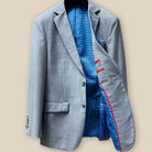 Interior view of light grey suit jacket showing light blue lining with navy and red design on left side