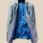 Full interior view of light grey suit jacket revealing light blue lining with intricate navy and red pattern