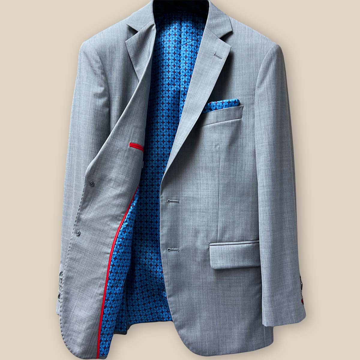 Interior right side of light grey suit jacket displaying red piping and trimming details