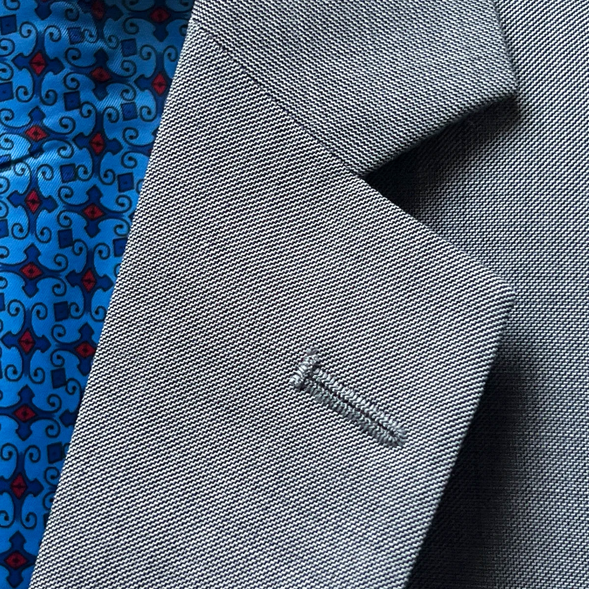 Detailed view of notch lapel on light grey sharkskin suit jacket