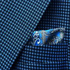 Breast pocket of medium blue micro check sport coat with matching paisley pocket square and hand-finished edges