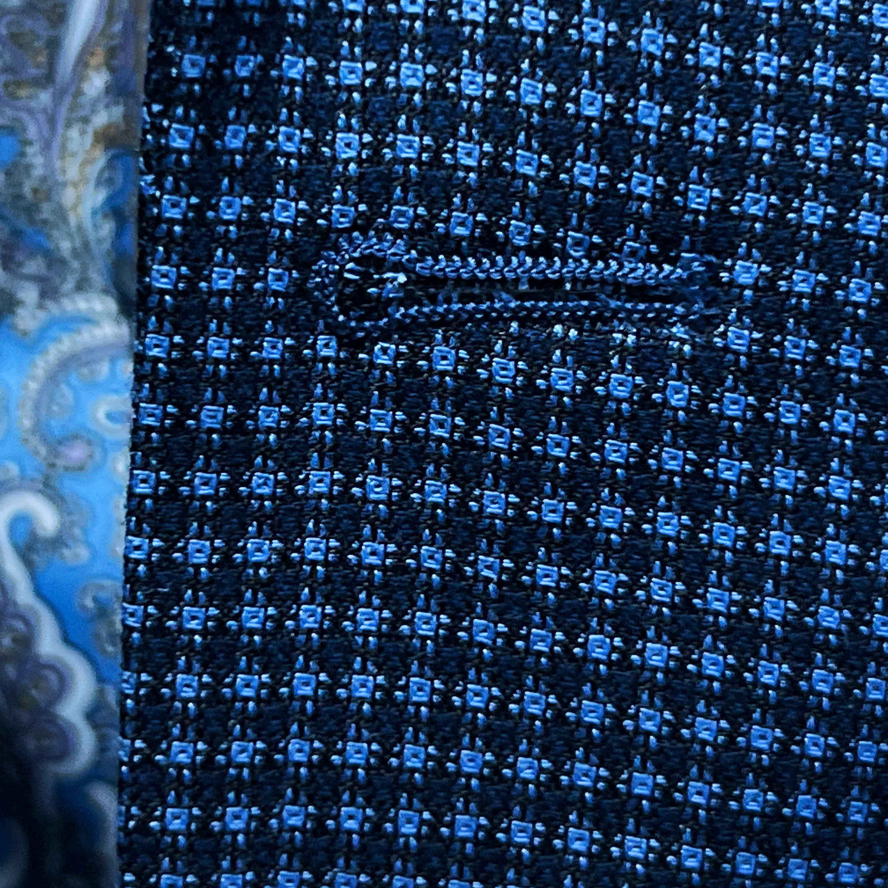 Detailed macro shot of hand-finished buttonhole stitching on medium blue micro check sport coat with light blue contrast thread