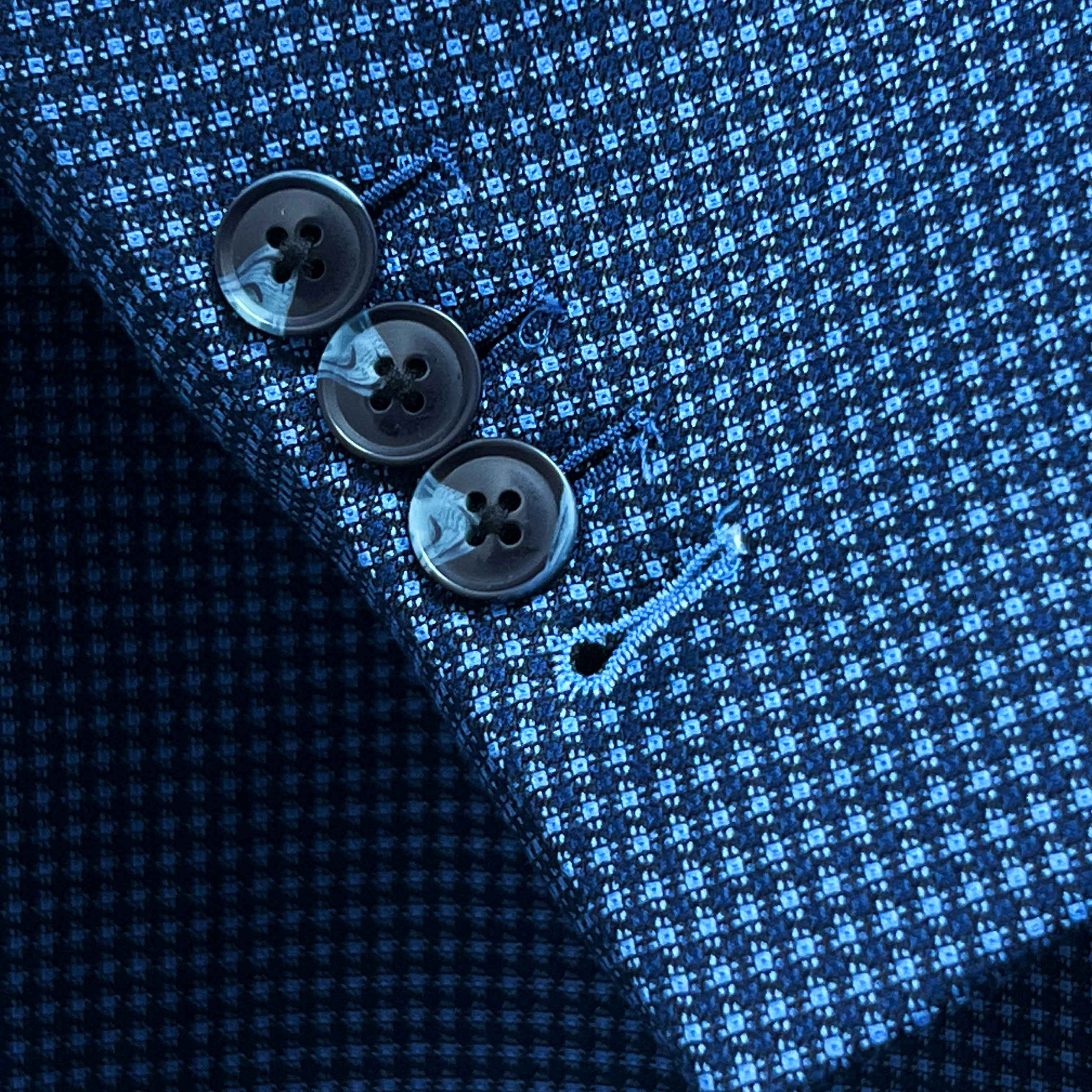 Sport coat sleeve cuff showing functional buttonholes with contrast light blue accent stitching on medium blue micro check fabric