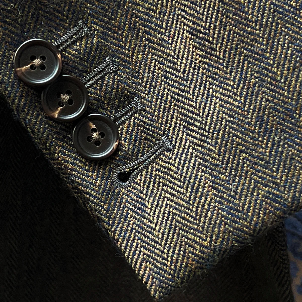 Working sleeve buttonholes detail demonstrating authentic tailoring with functional walnut brown horn buttons on jacket cuff