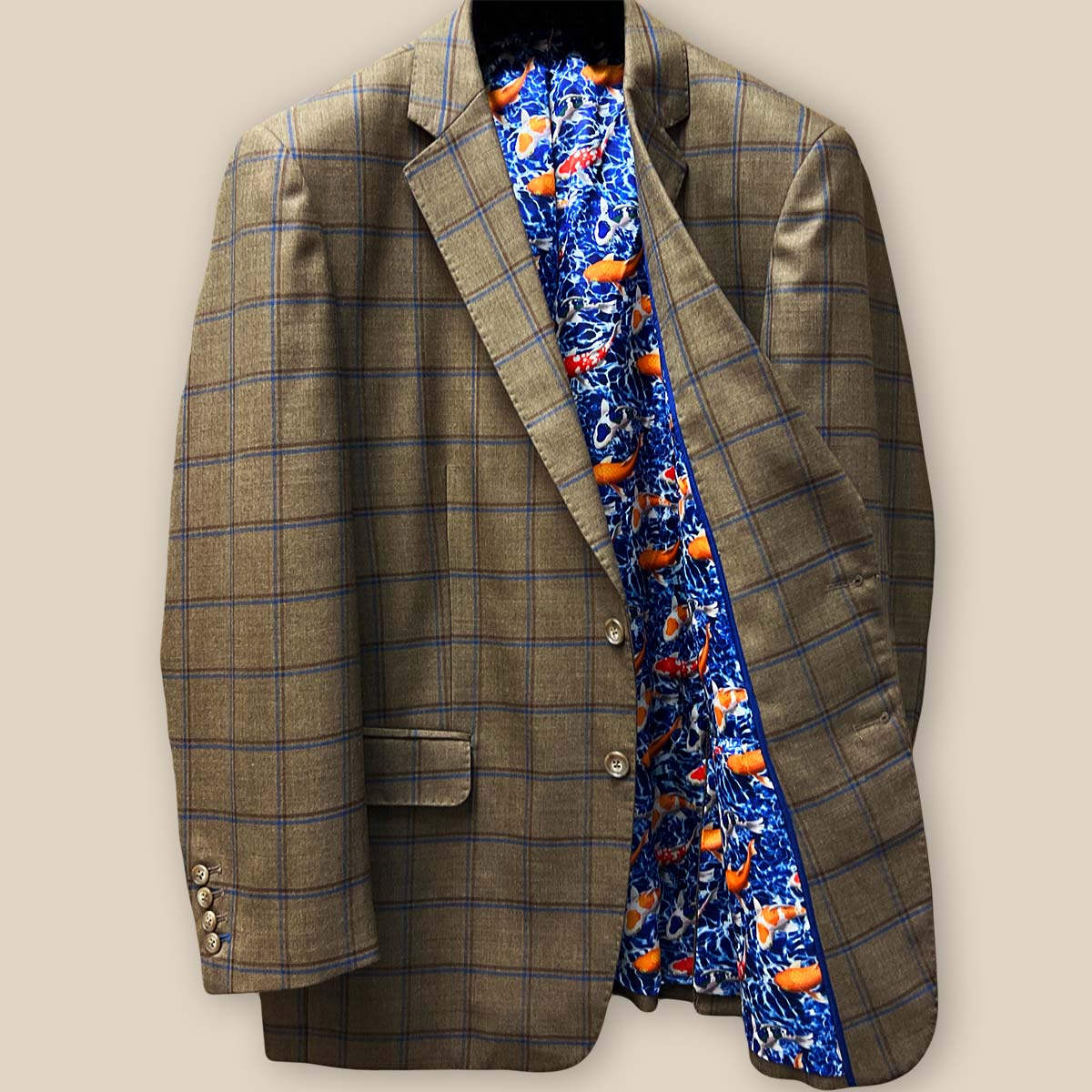 Interior view of left side of medium brown sport coat, displaying royal blue lining with vibrant goldfish and koi fish pattern