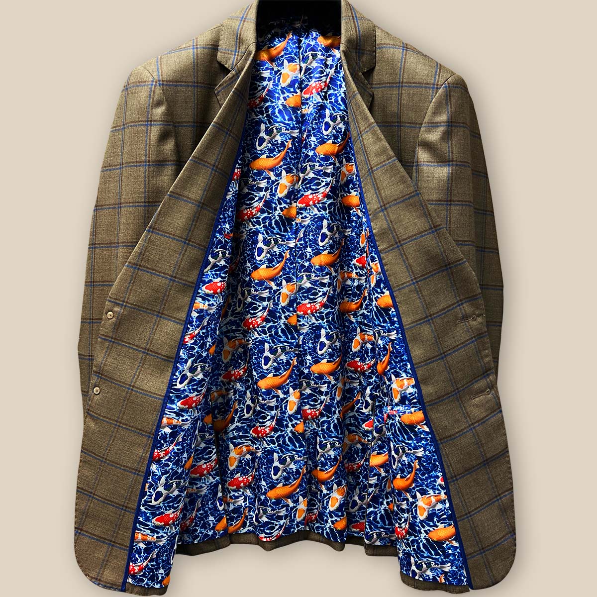 Full view of opened medium brown sport coat, revealing entire royal blue lining with swimming goldfish and koi fish motif