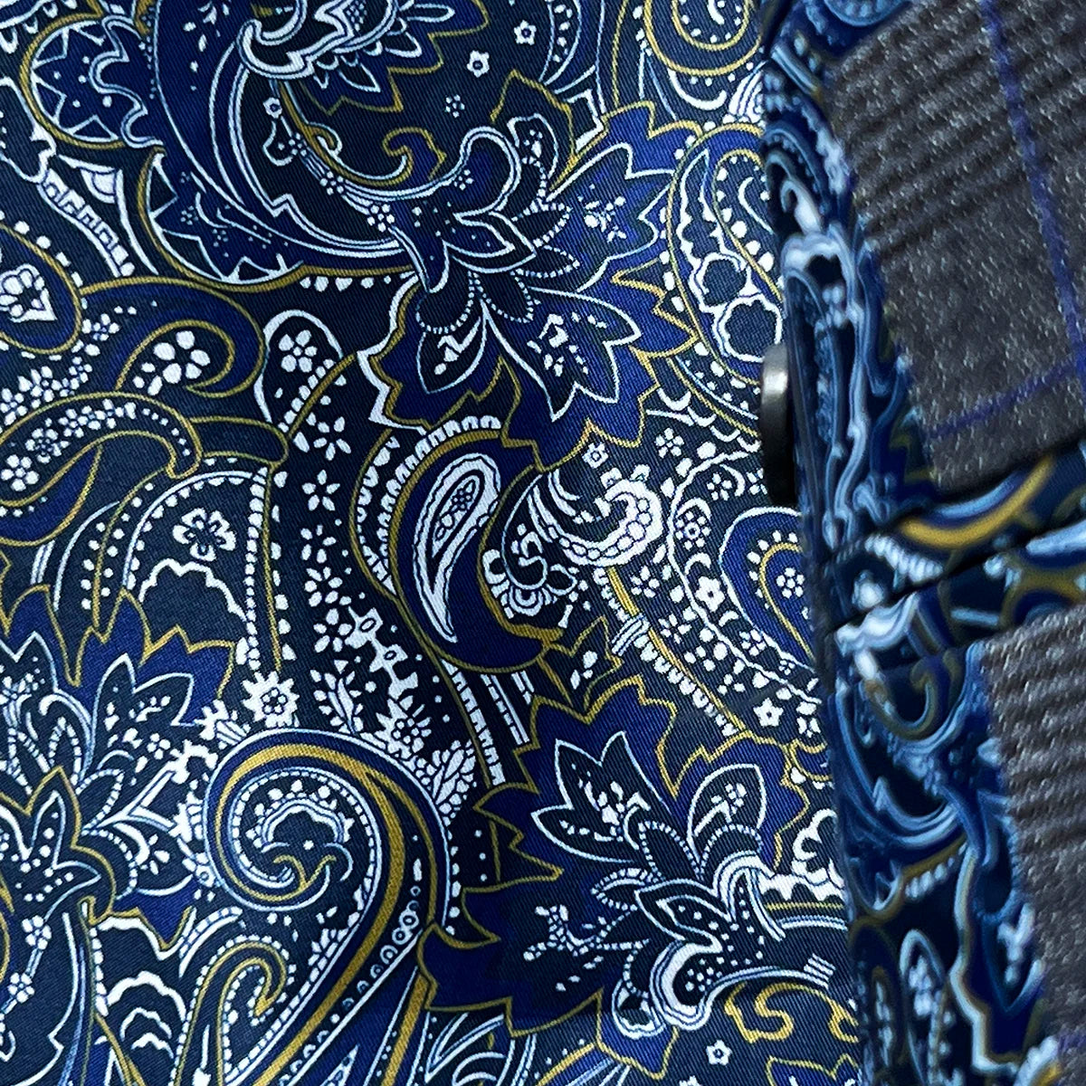 Close-up of the vibrant blue paisley lining with gold and white accents visible when the jacket moves, adding a flash of personality to the conservative exterior