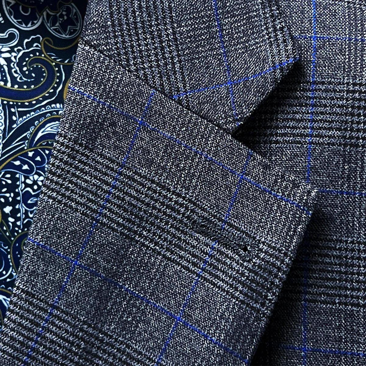 Detailed view of the classic notch lapel on the medium grey suit jacket with visible pick stitching, showing the clean lines and balanced proportions