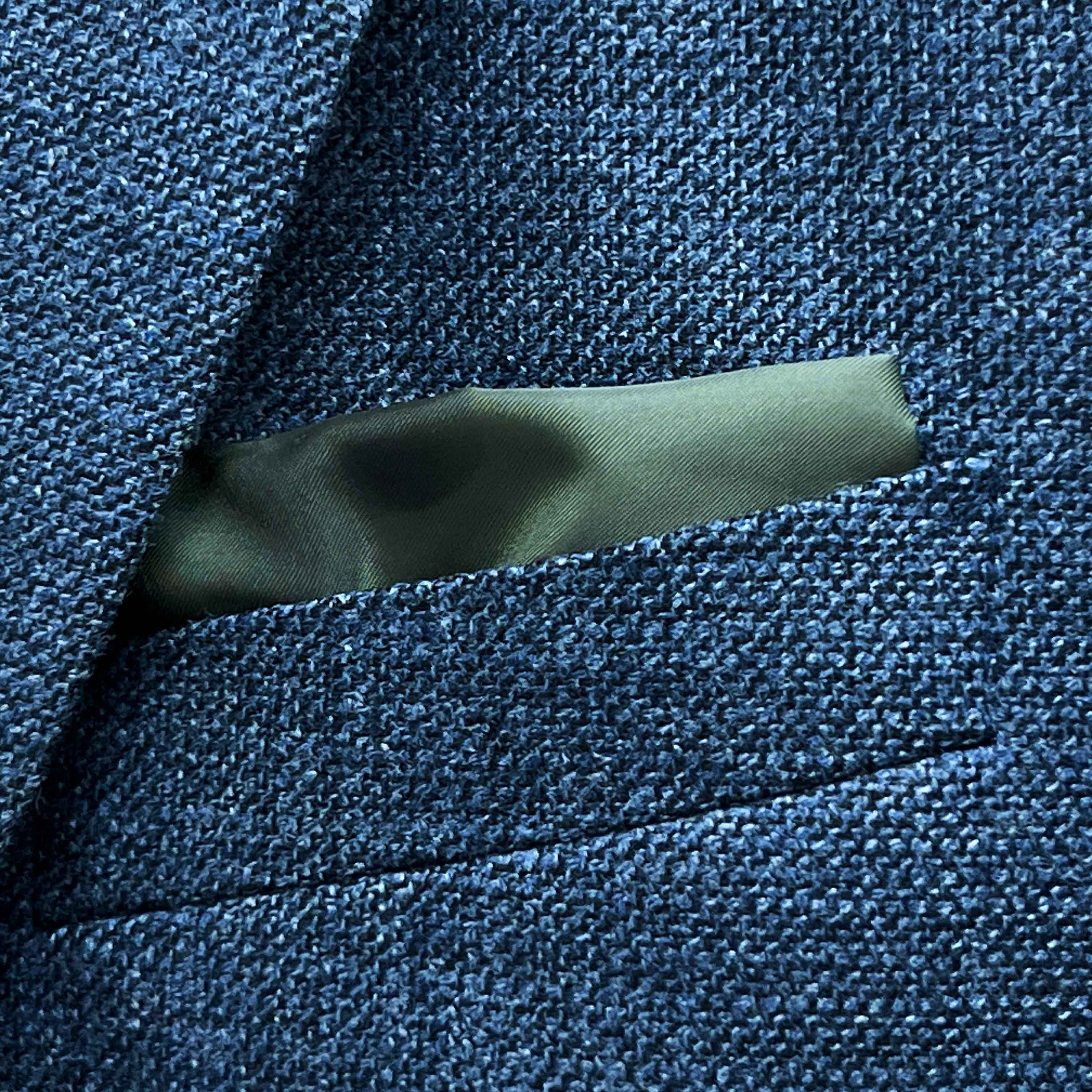 Breast pocket of medium steel blue hopsack sport coat with built-in pocket square holder and hand-finished edges
