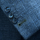 Sport coat sleeve cuff showing functional buttonholes with olive green contrast accent stitching on medium steel blue hopsack fabric