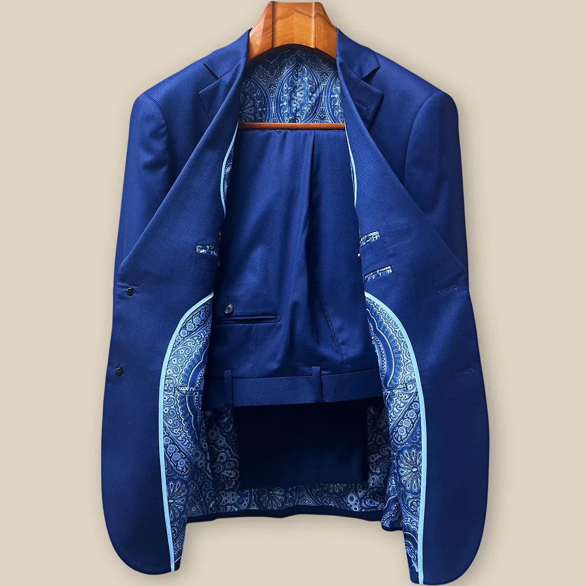 Complete two-piece navy blue geometric textured custom suit displayed on hanger showing jacket and trousers