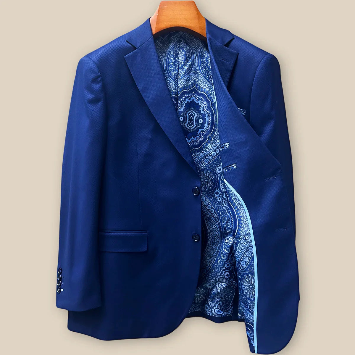 Interior left side of navy blue geometric textured suit jacket displaying rich blue intricate paisley lining with inner pocket