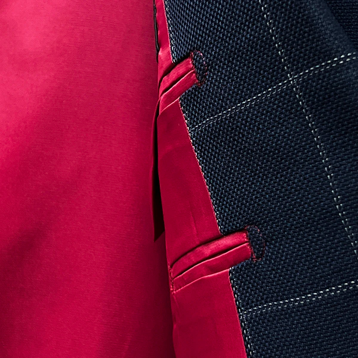 Close-up texture shot of tomato red silk bemberg lining used in navy windowpane suit