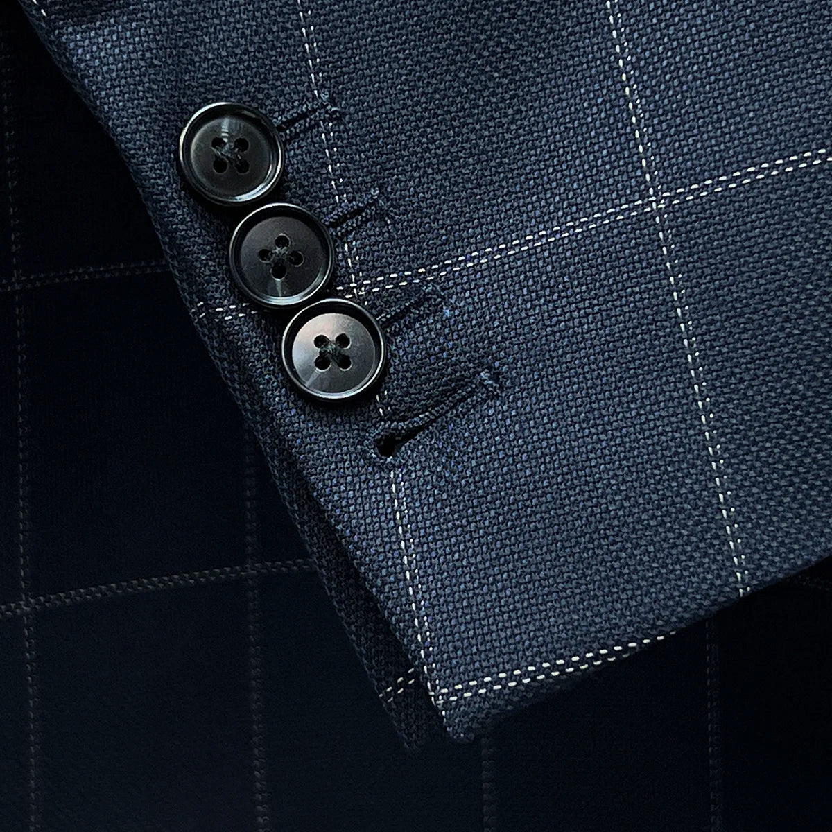 Detail shot of functional buttonholes on suit jacket sleeve, showcasing fine stitching