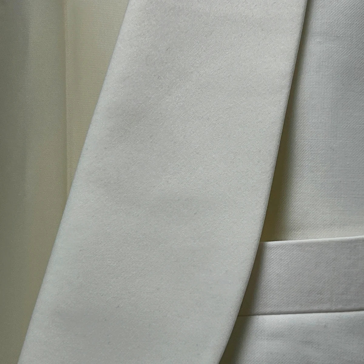 Detailed view of the Westwood Hart dinner jacket's elegant off-white silk satin shawl lapel, showcasing its smooth curve and lustrous finish