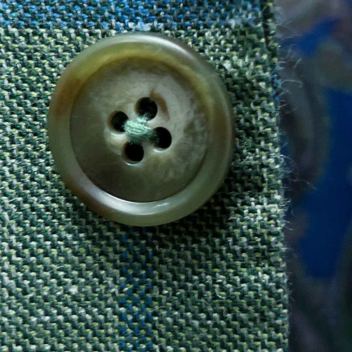 Detailed view of olive green horn buttons showcasing natural marble patterns and expert shank attachment
