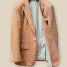 Interior view of orange suit jacket's left side, showcasing ivory paisley flash lining and bright orange piping