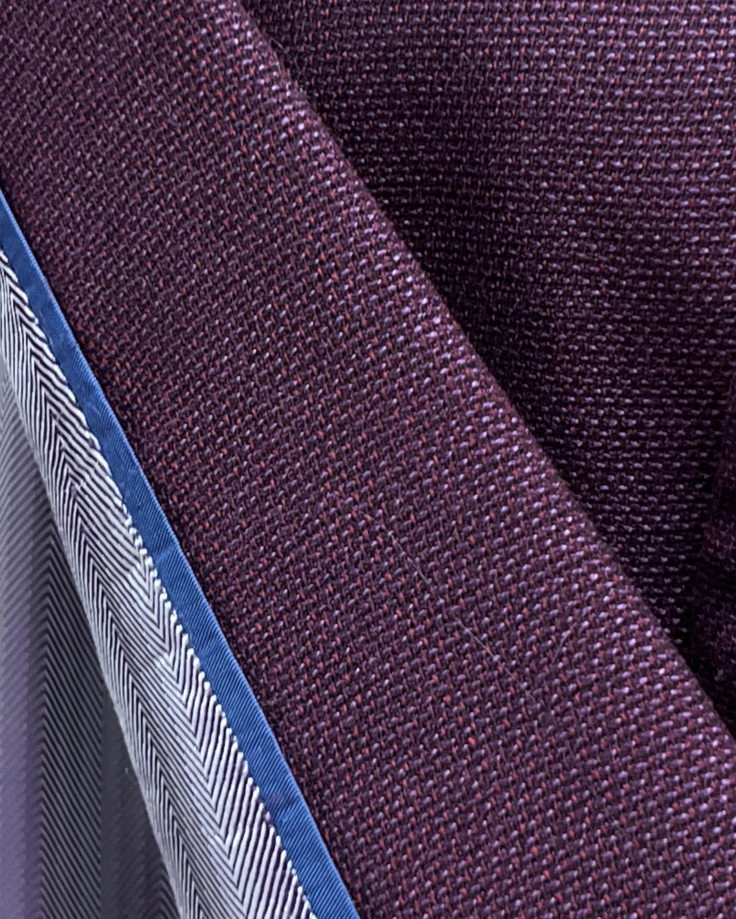 Fabric close up of deep plum burgundy birdseye men's sport coat showing textured cloth surface