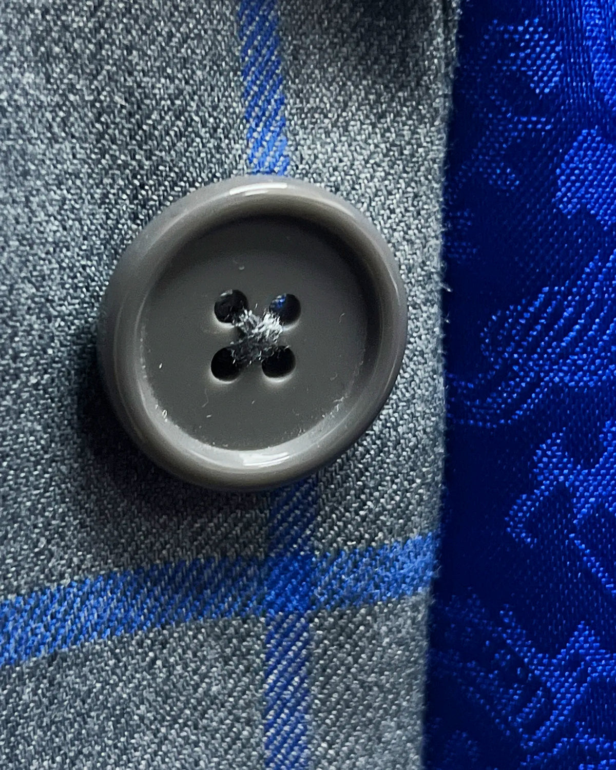 Dark grey horn buttons of mid heather grey royal blue windowpane men's sport coat showing button detail
