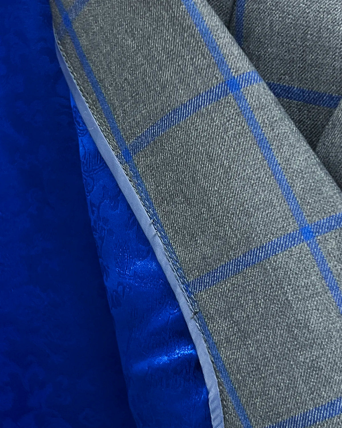 Fabric close up of mid heather grey royal blue windowpane men's sport coat showing cloth texture and windowpane weave