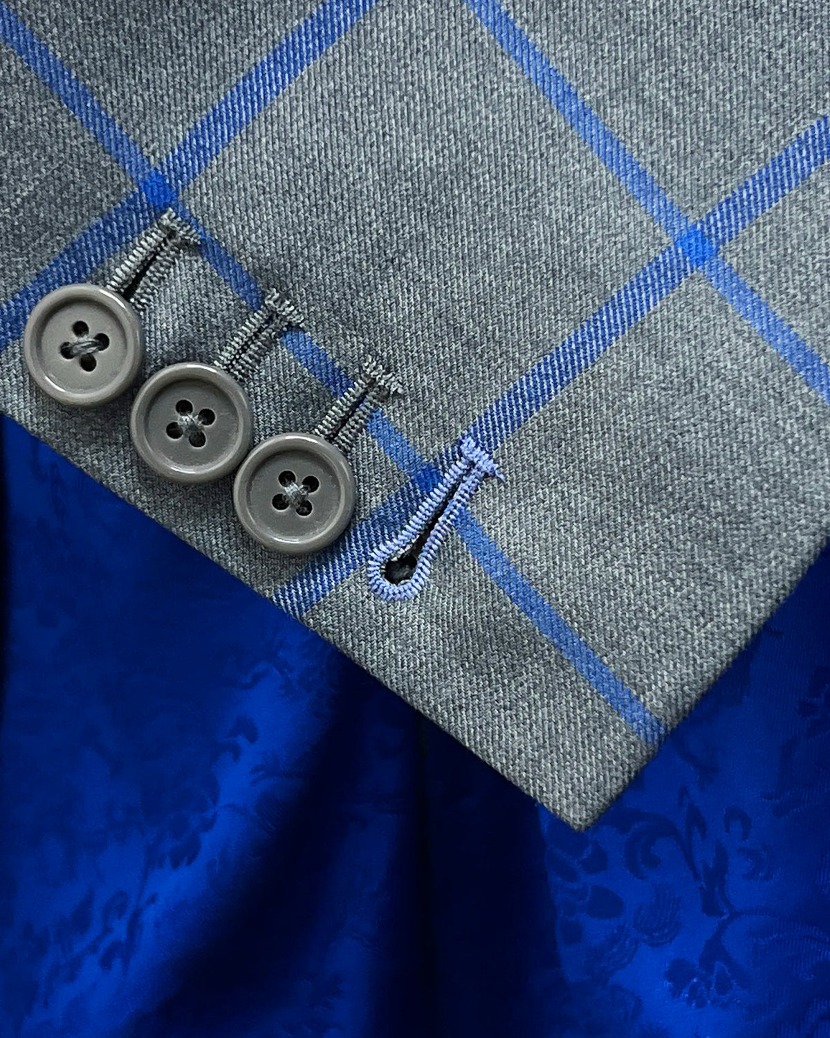 Functional sleeve buttons of mid heather grey royal blue windowpane men's sport coat showing the light blue contrast last buttonhole
