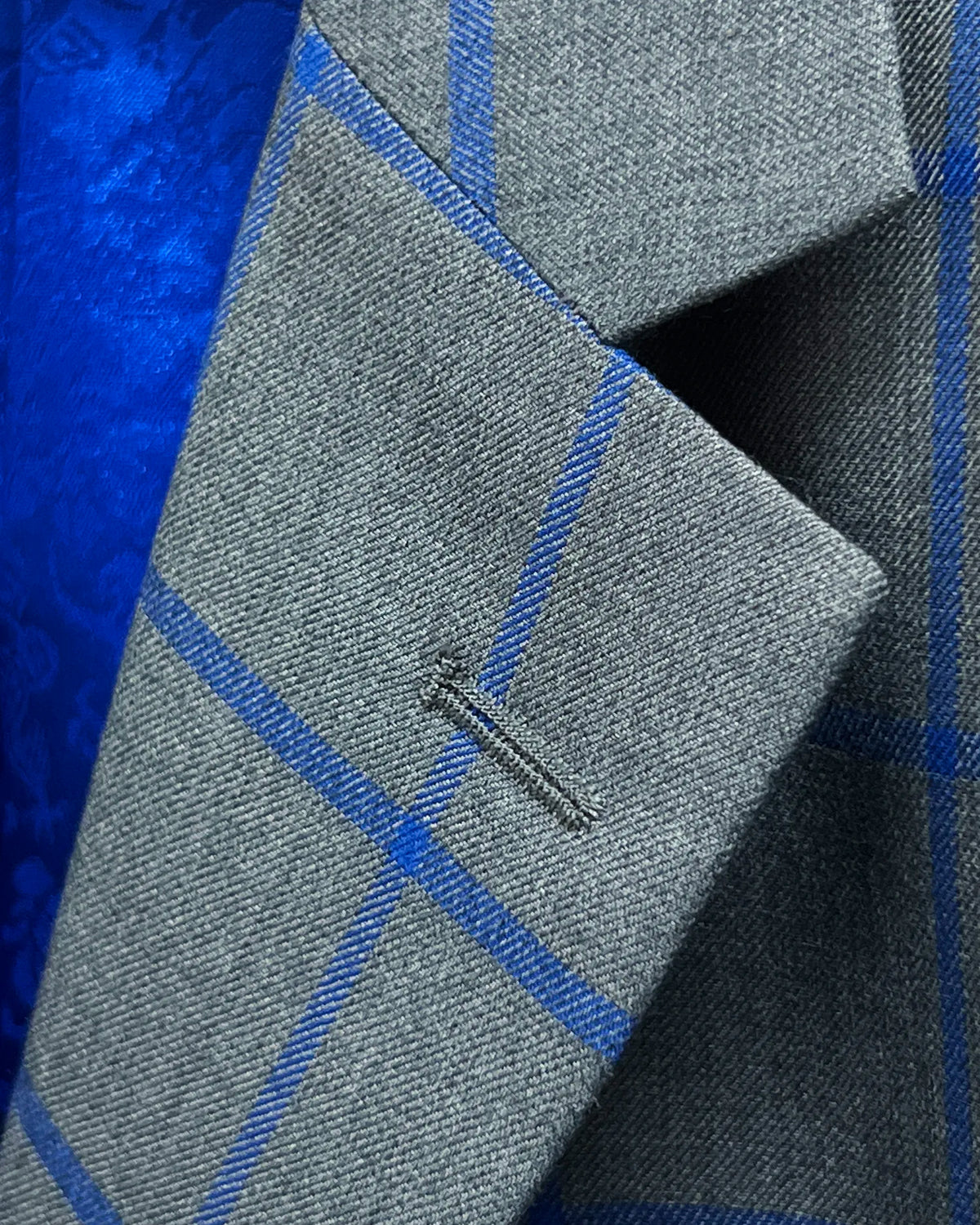 Lapel buttonhole detail of mid heather grey royal blue windowpane men's sport coat showing standard stitching