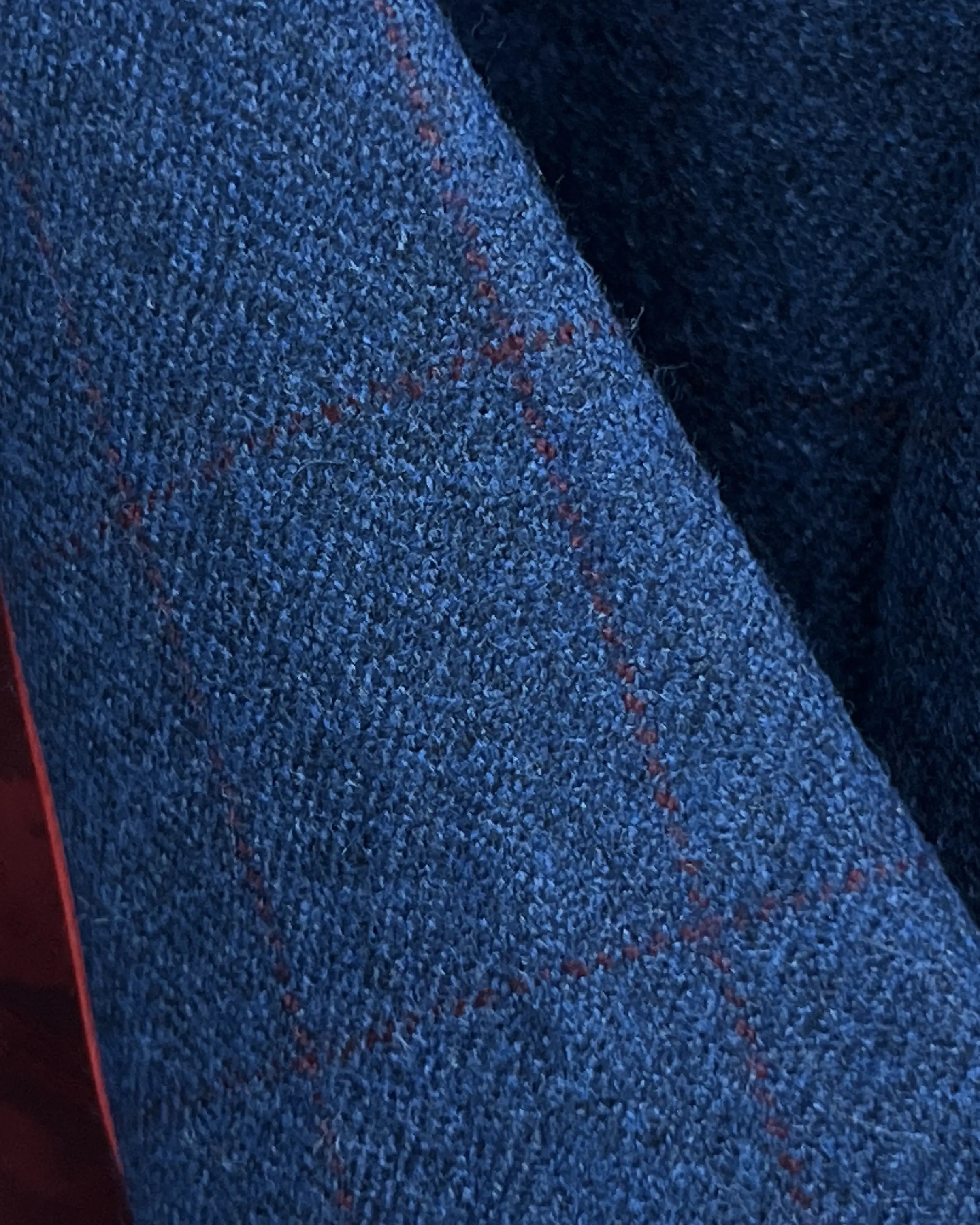 Fabric close up of teal blue with red windowpane men's sport coat showing the cloth texture and surface character