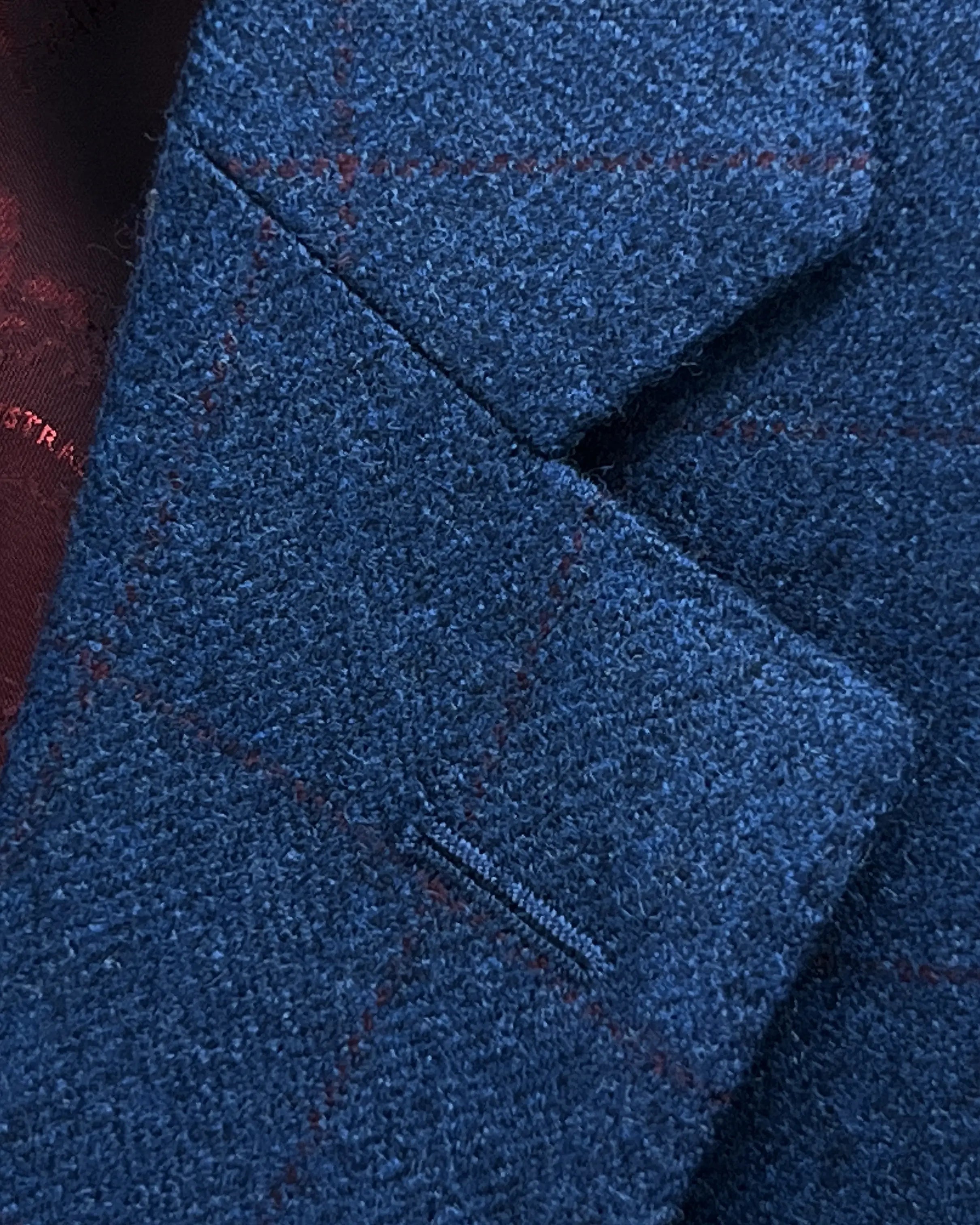 Lapel detail of teal blue with red windowpane men's sport coat showing the standard lapel buttonhole