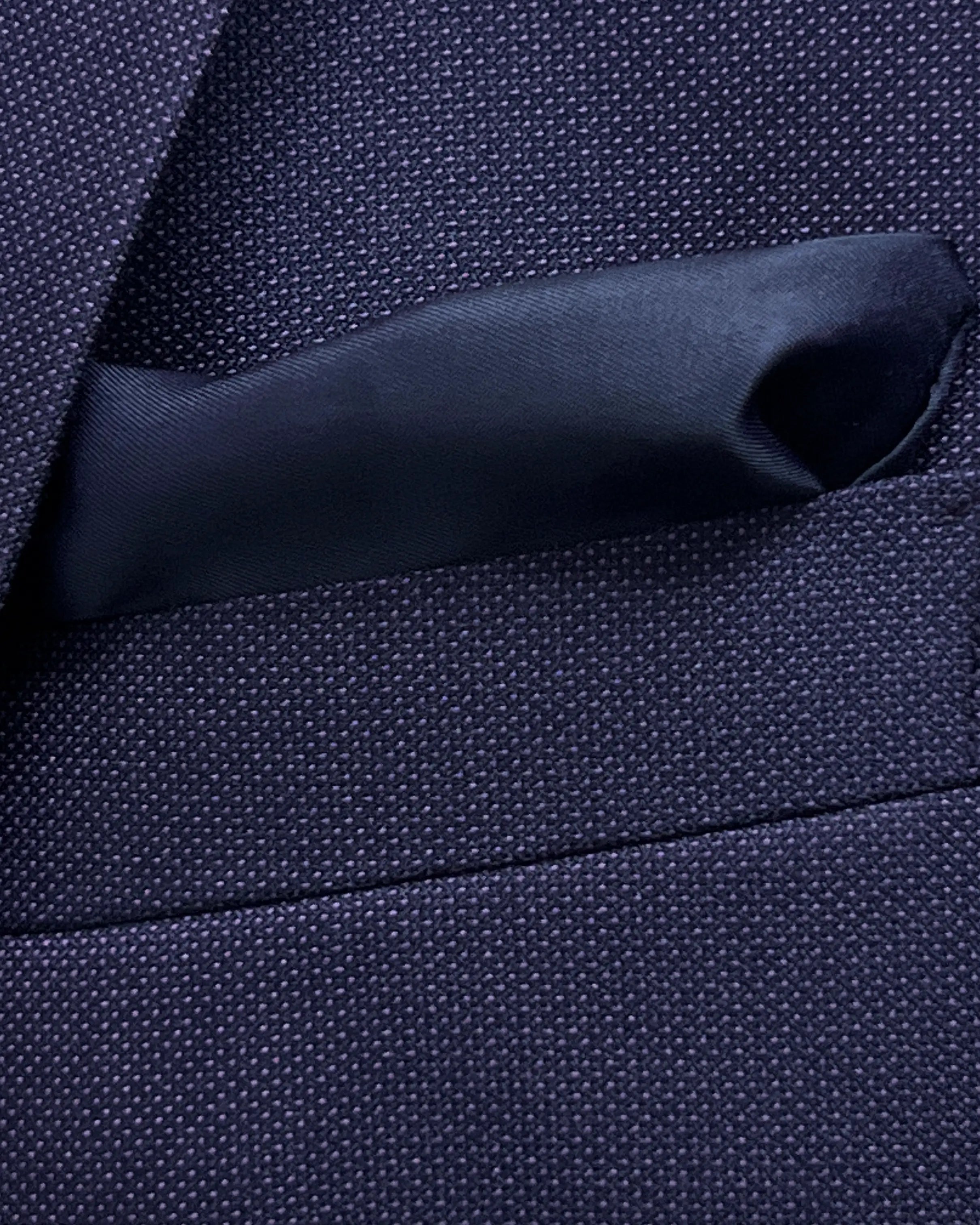 Breast pocket detail of aubergine birdseye men's suit showing the dark navy cupro silk bemberg pocket square.