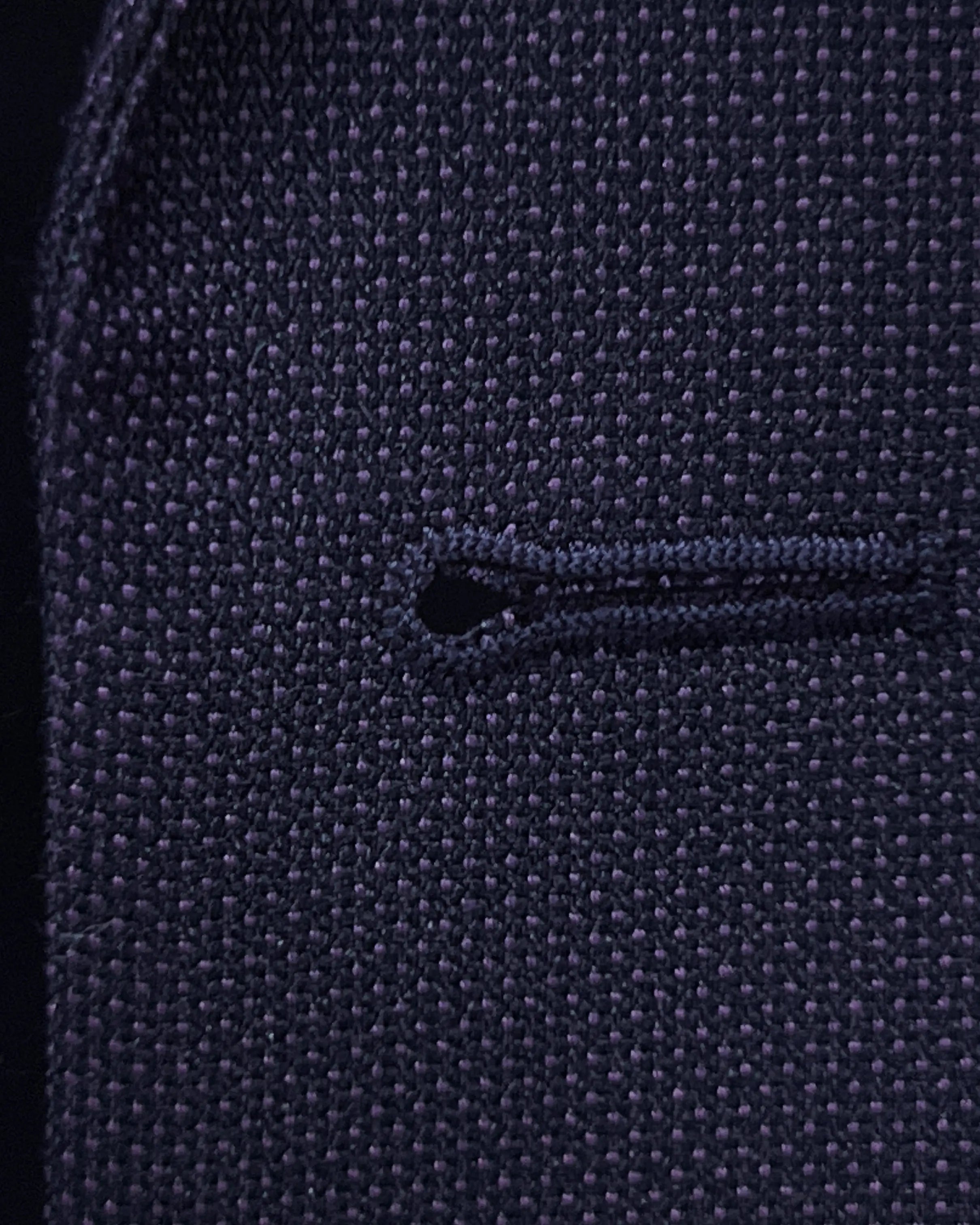 Front buttonhole close up of aubergine birdseye men's suit showing standard matching stitching.