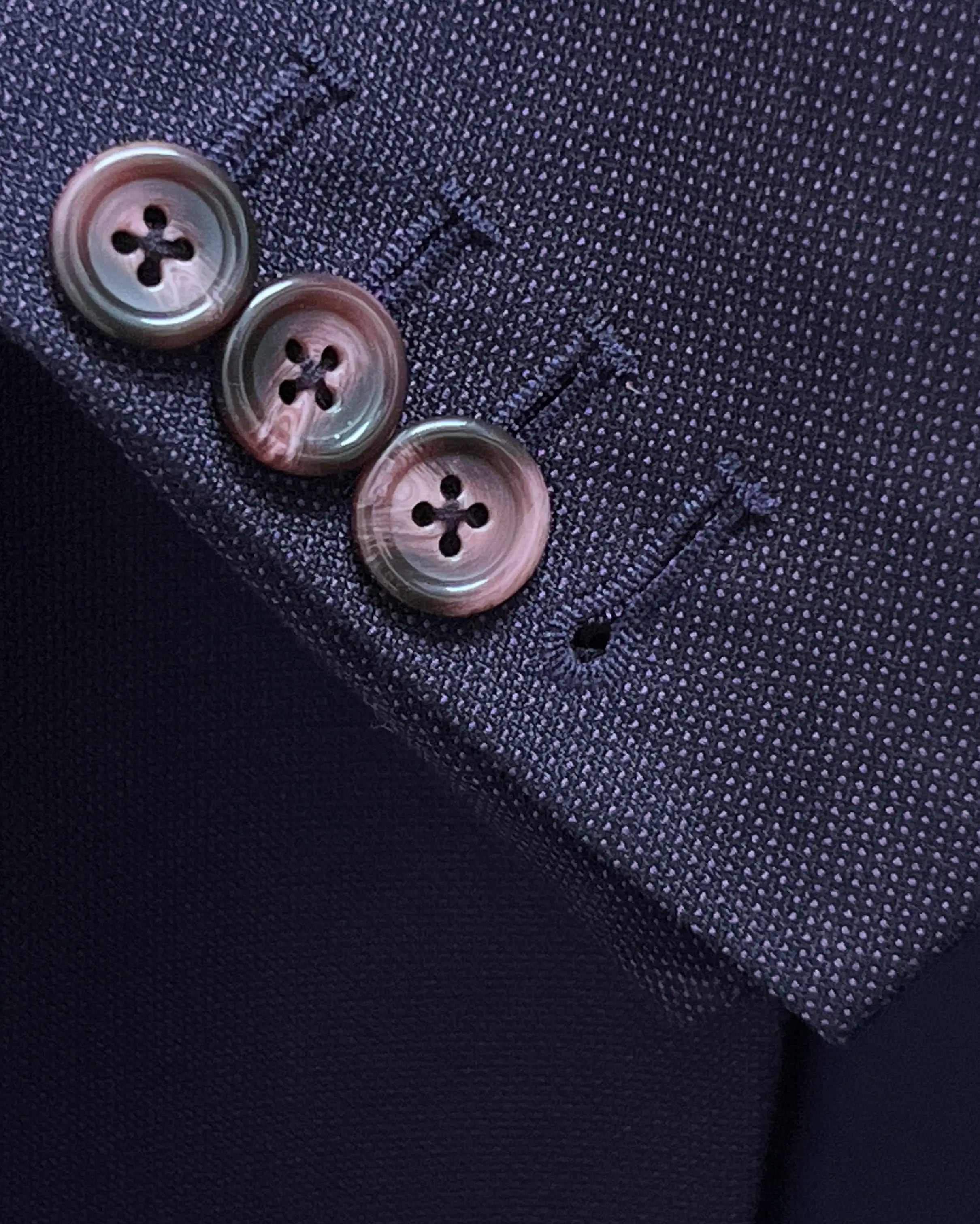 Sleeve cuff close up of aubergine birdseye men's suit showing functional sleeve buttons with matching thread.