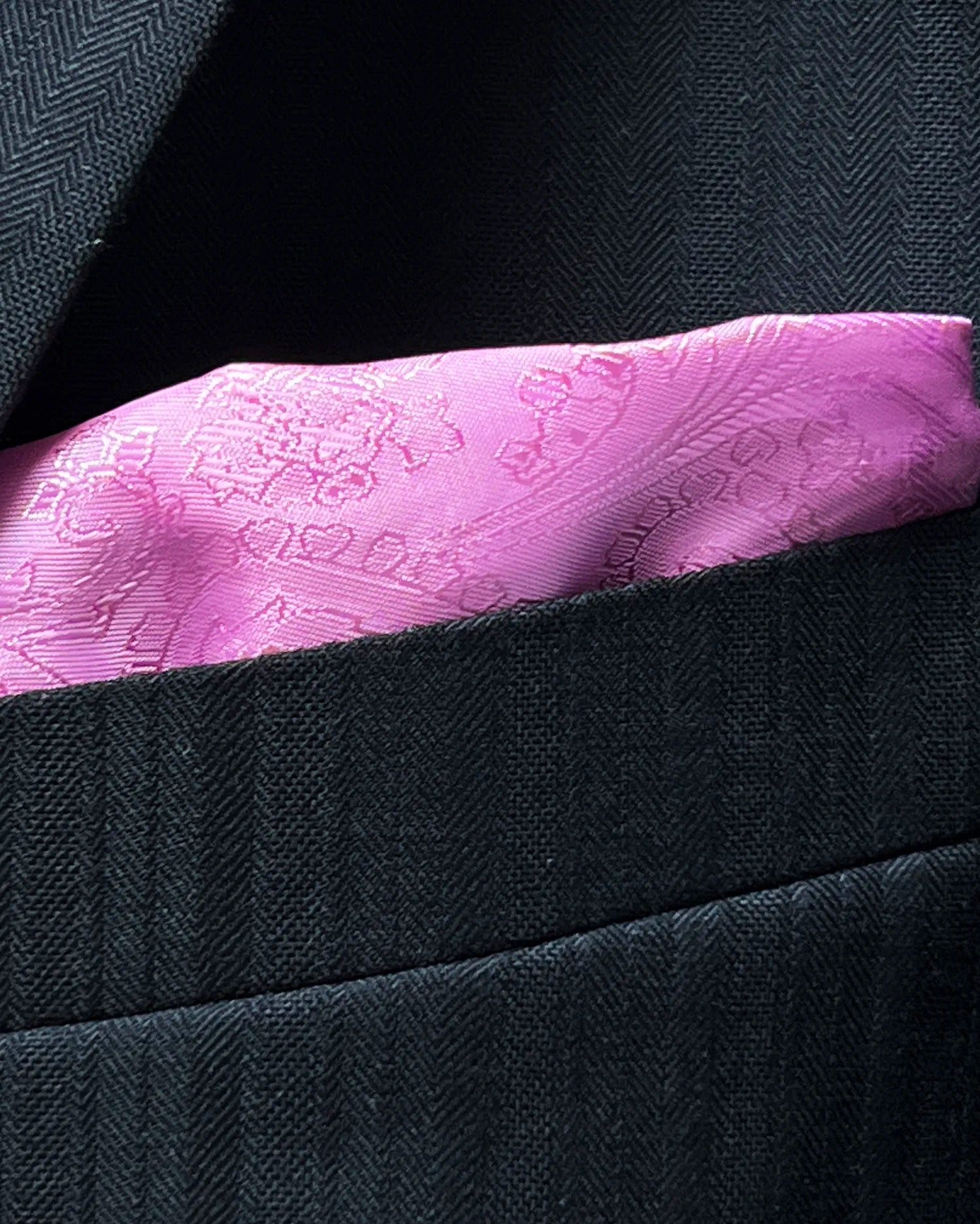 Breast pocket detail of black herringbone with shadow stripes men's suit showing the matching lining pocket square