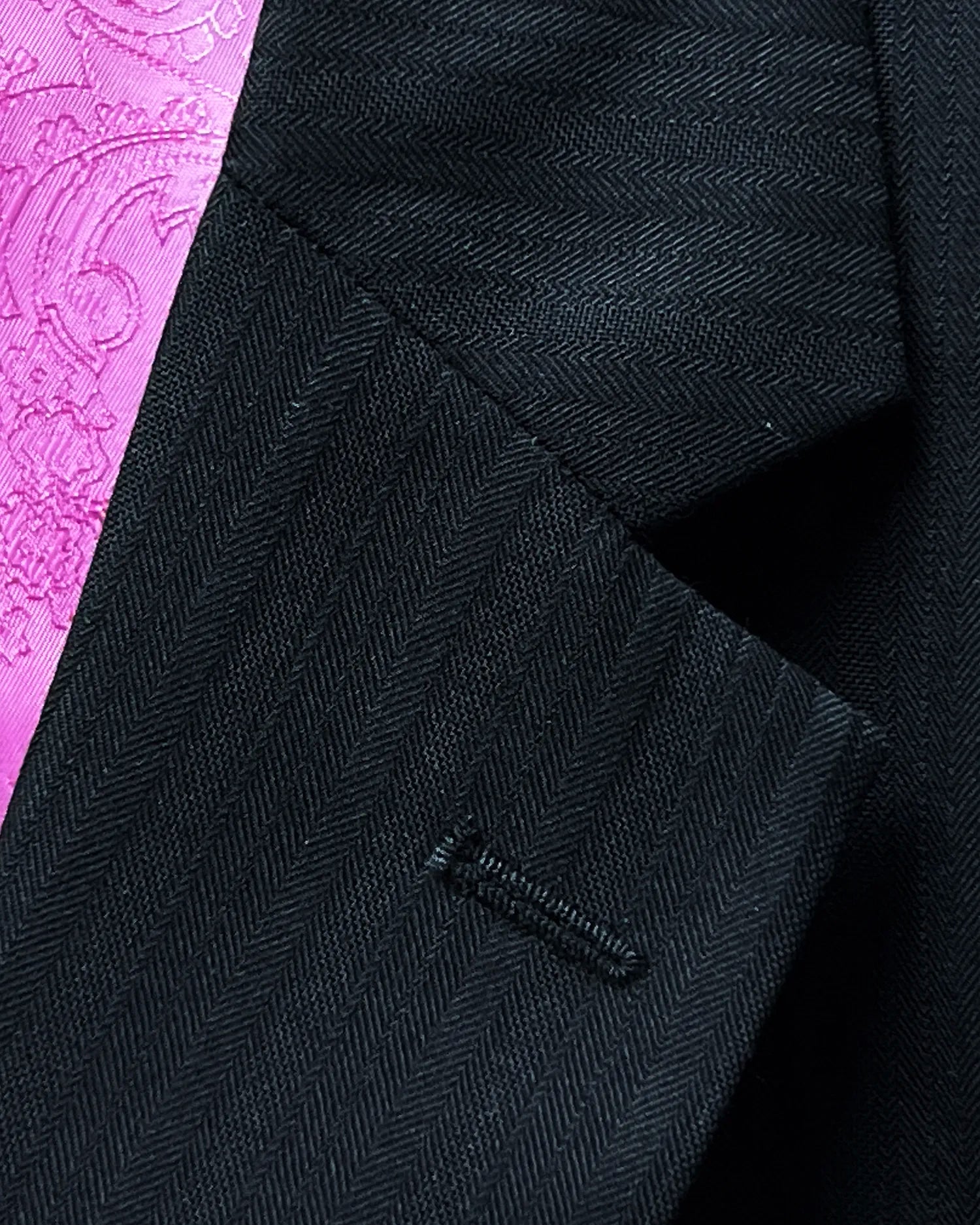 Lapel detail of black herringbone with shadow stripes men's suit showing the standard lapel buttonhole