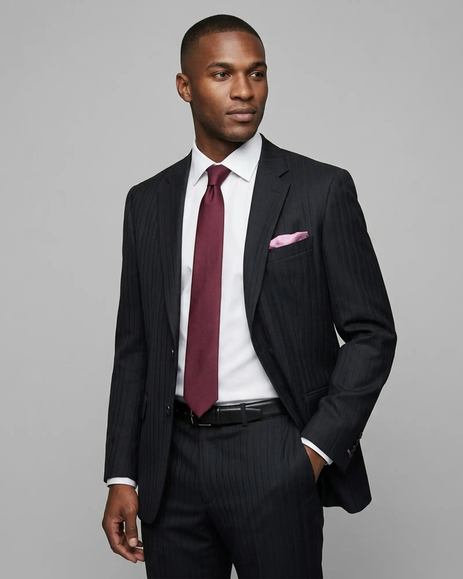 Model alternate side view of black herringbone with shadow stripes men's suit showing the lapel and tailored fit