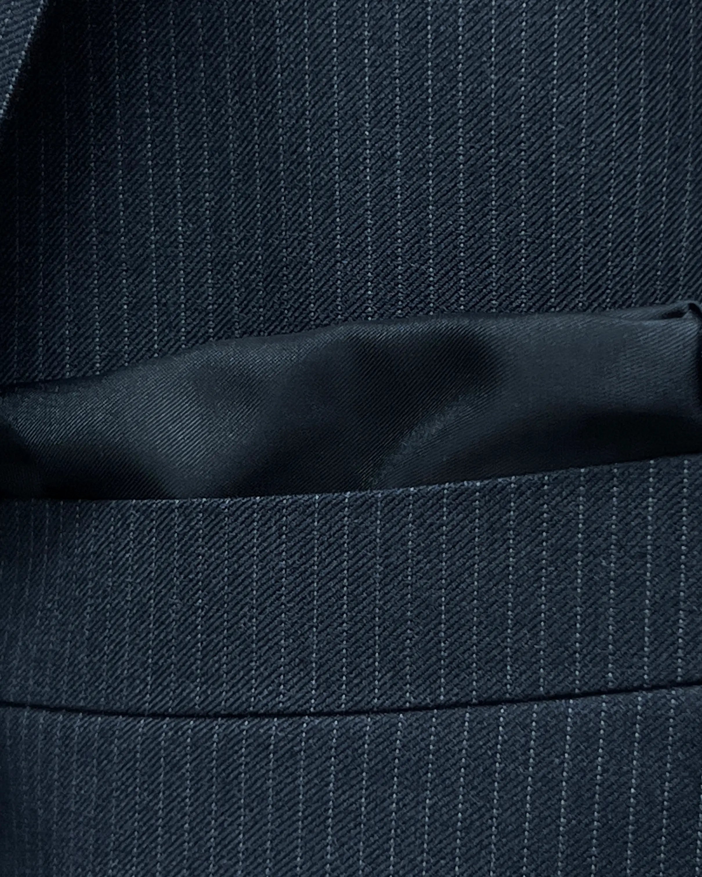 Breast pocket detail of black pinstripe men's suit showing the built in black silk cupro Bemberg pocket square
