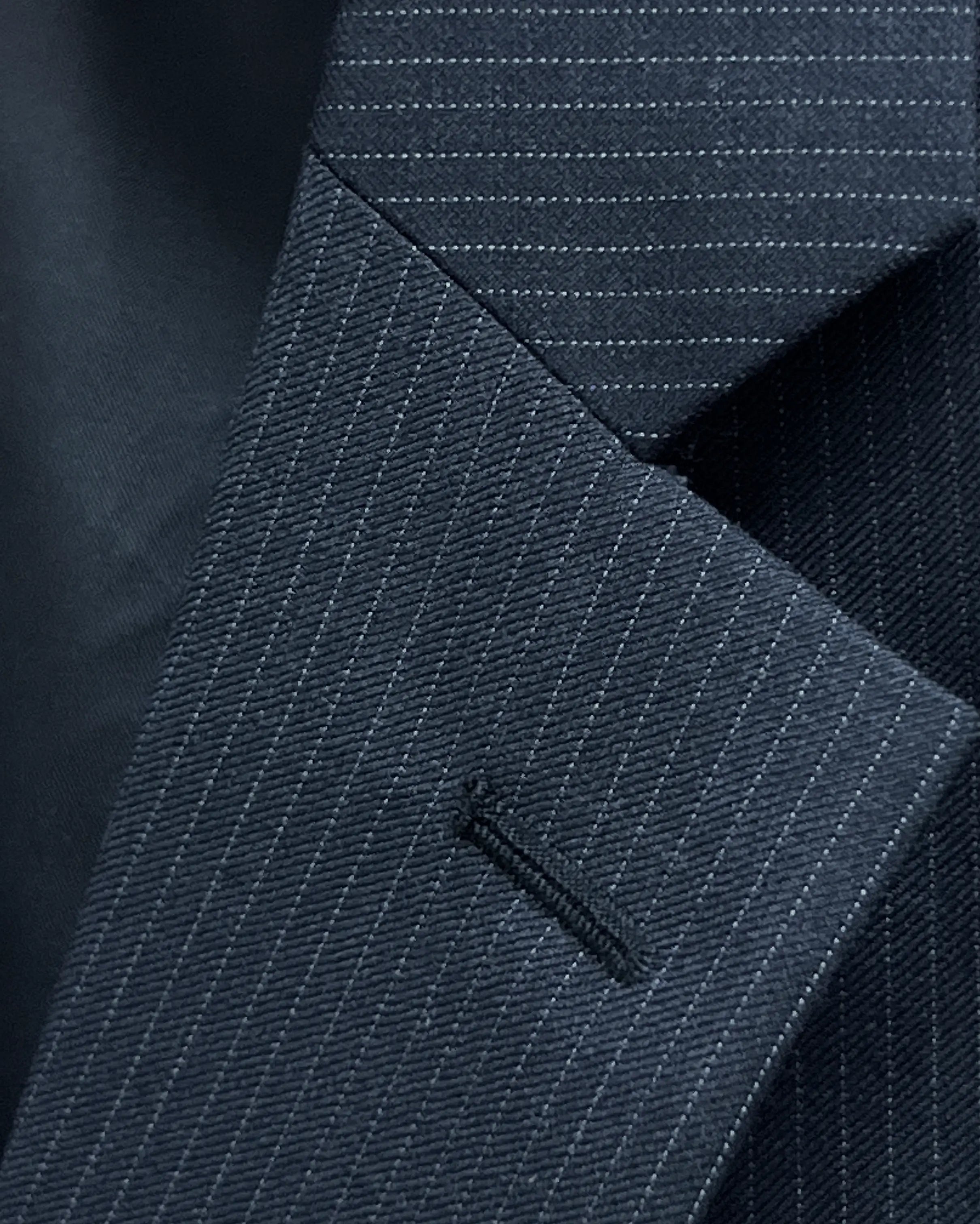 Notch lapel buttonhole detail of black pinstripe men's suit showing standard matching thread construction