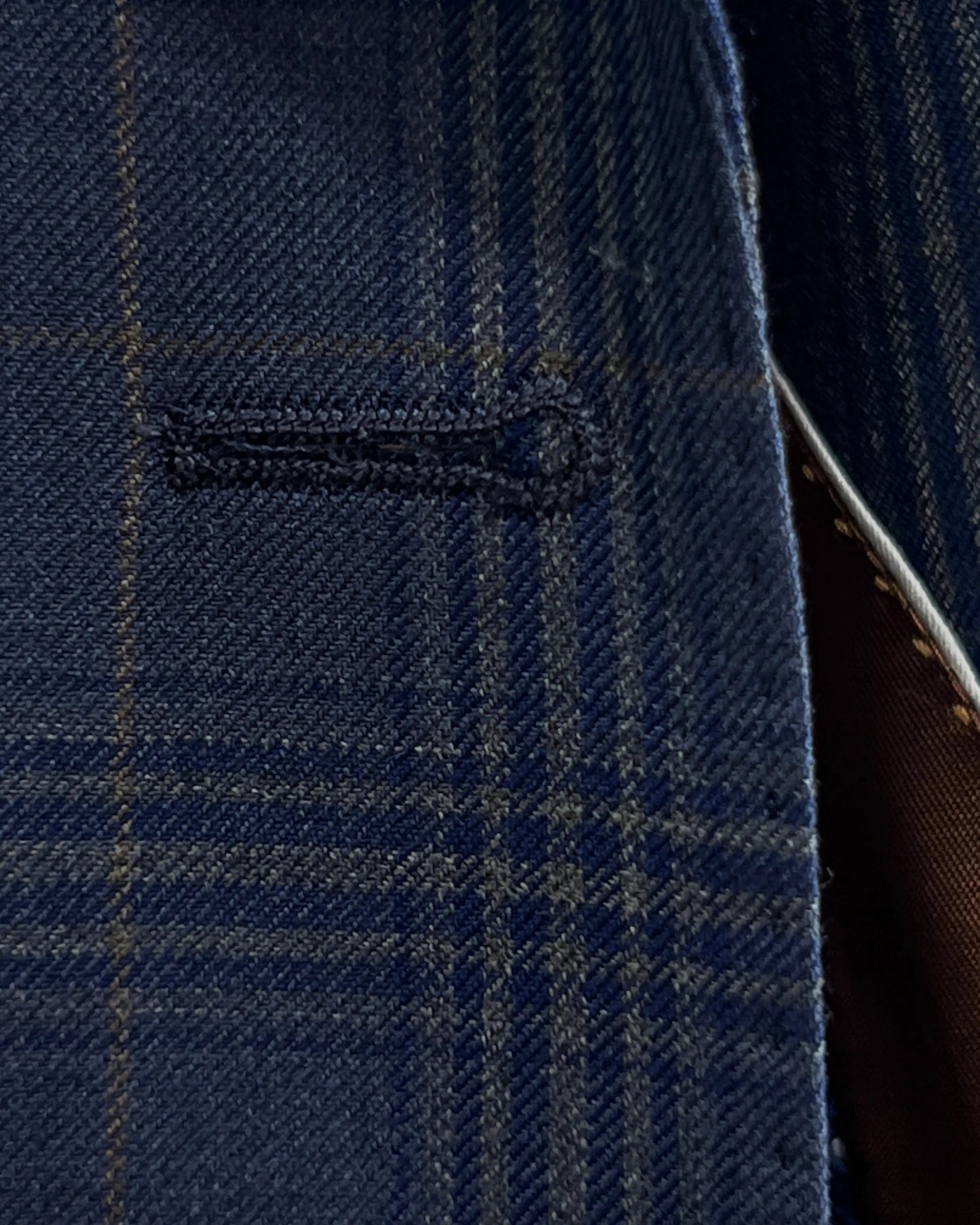 Buttonhole detail of blue windowpane plaid men's suit showing clean buttonhole stitching