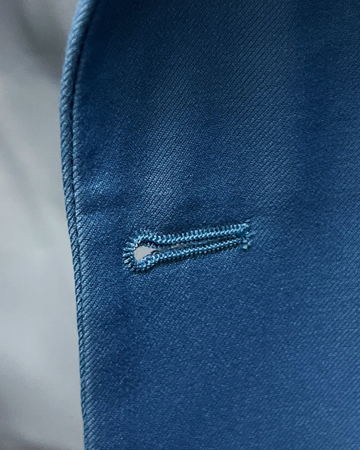 Detail of cornflower blue solid twill weave men's suit showing front buttonhole construction