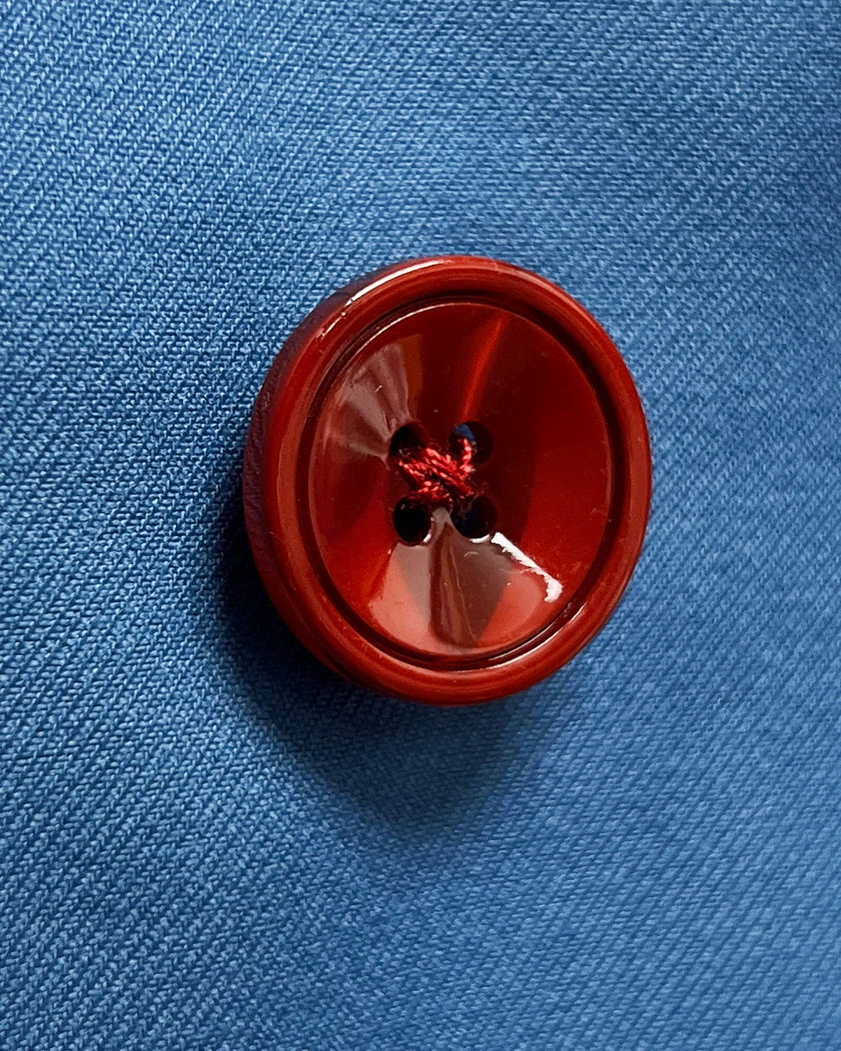 Detail of cornflower blue solid twill weave men's suit showing deep burgundy corozo buttons