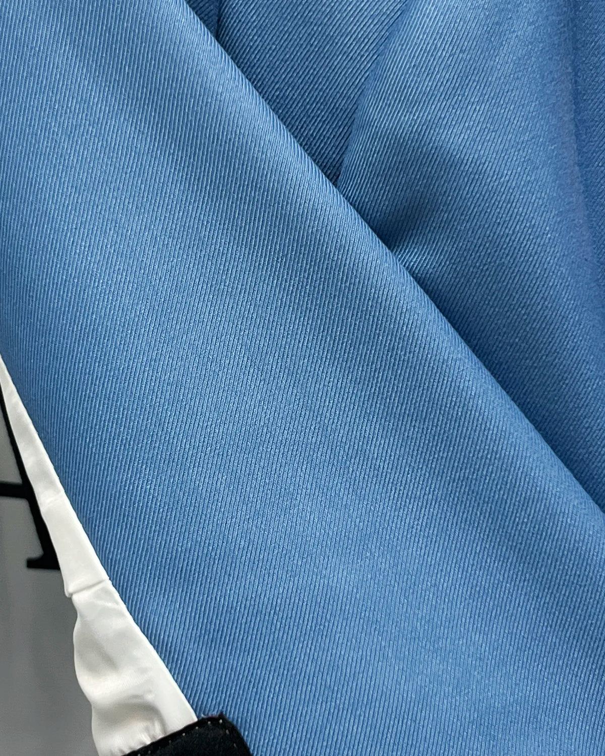 Fabric close up of cornflower blue solid twill weave men's suit showing fine twill cloth texture