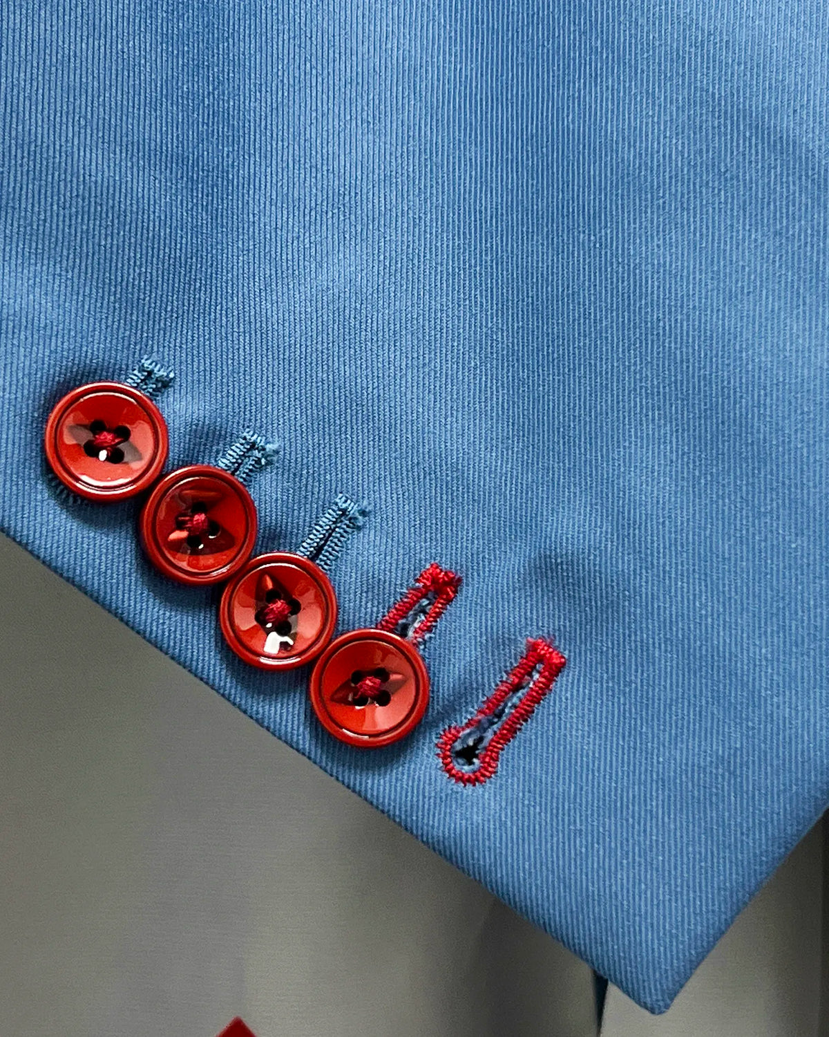 Sleeve detail of cornflower blue solid twill weave men's suit showing functional cuff buttons and contrast buttonhole
