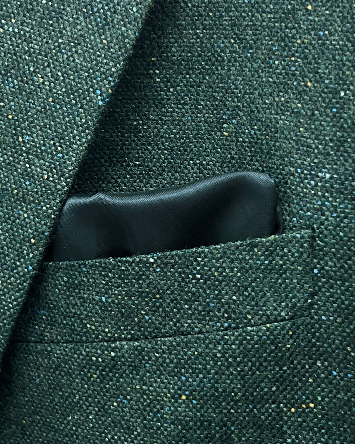 Pocket detail of dark forest green Donegal tweed men's suit showing the built in lining pocket square