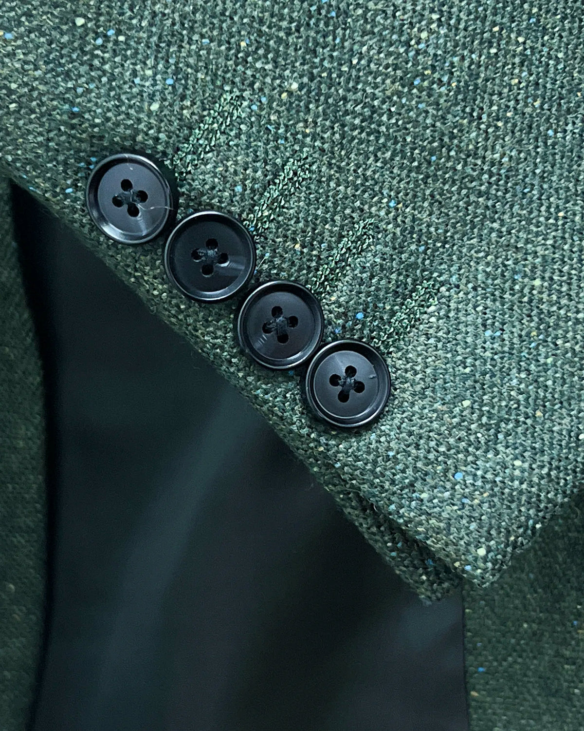 Sleeve detail of dark forest green Donegal tweed men's suit showing functional sleeve buttons and matching buttonholes