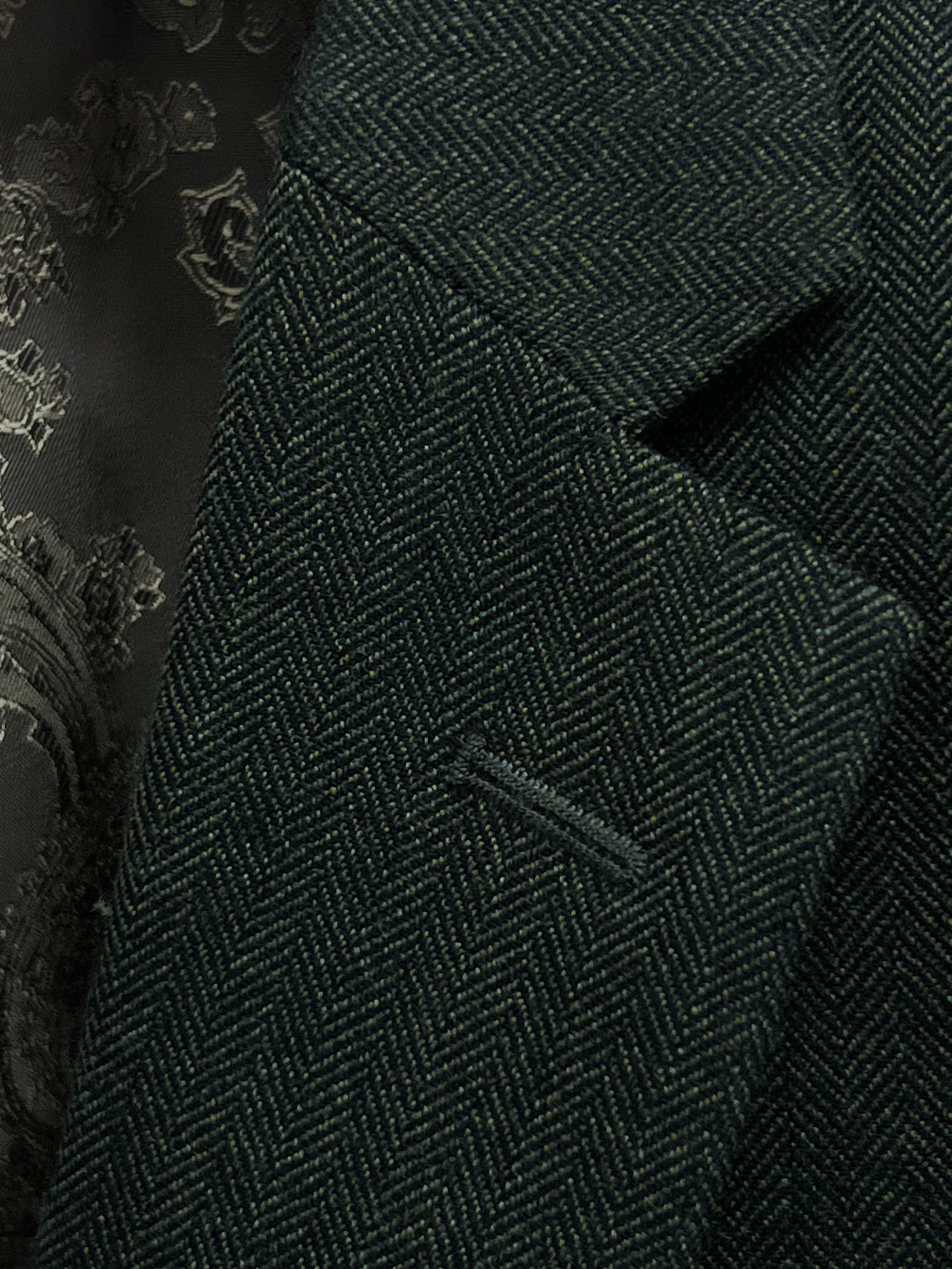 Lapel close up of dark forest green herringbone men's suit showing standard lapel buttonhole